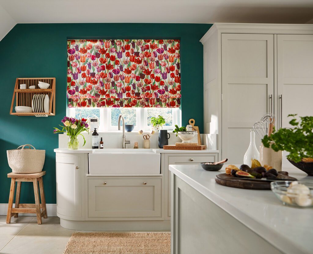 Image shows a kitchen interior with a brightly coloured roman blind over the window in an Emma Bridgewater fabric called Tulips.