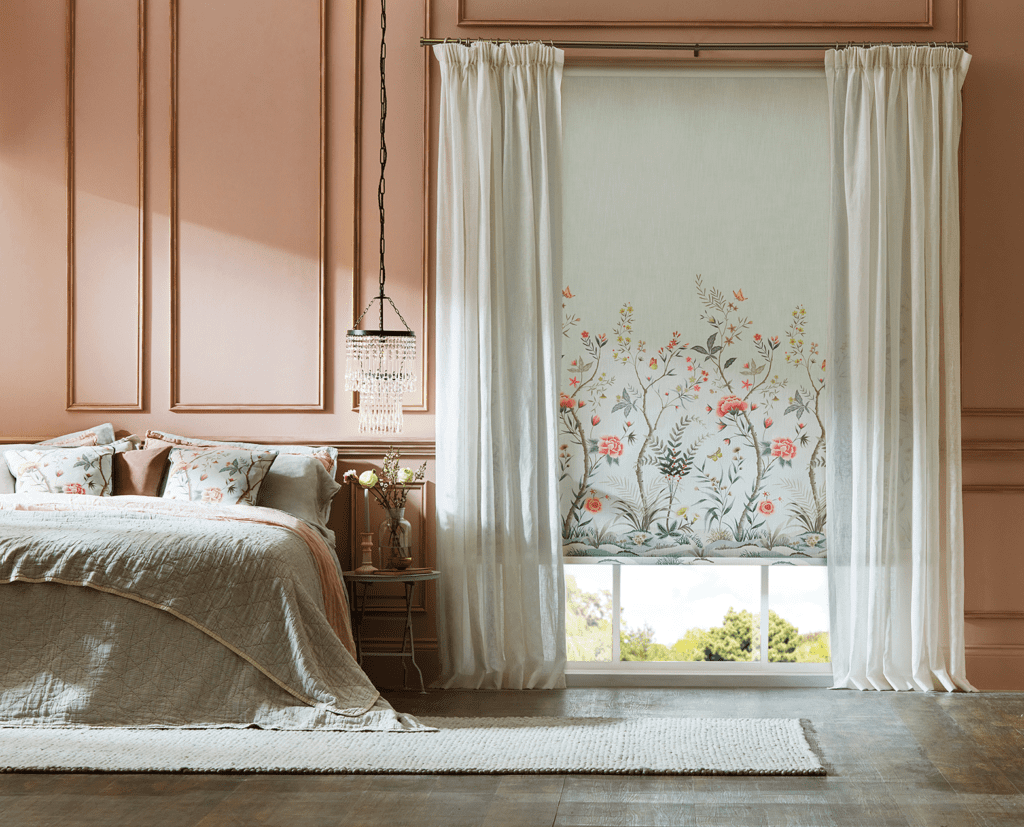 Image shows a blockout roller blind layered with white sheer curtains. 