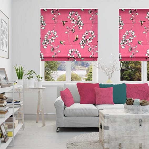 Bright pink roman blinds featuring a sweet print with flowers and hummingbirds cover the windows in this living room. 