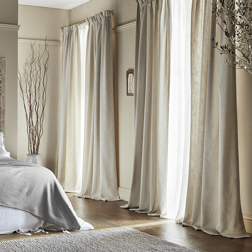Elegant double pinch pleat curtains in a bedroom.